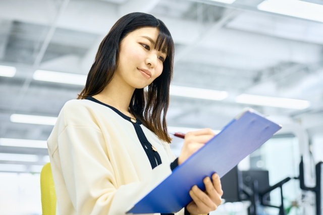 紙の手続き用紙を記入する女性